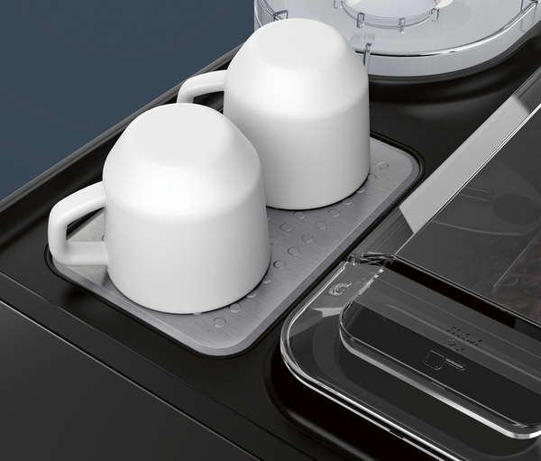 Zwei umgedrehte weiße Tassen auf einer schwarzen Kaffeemaschine