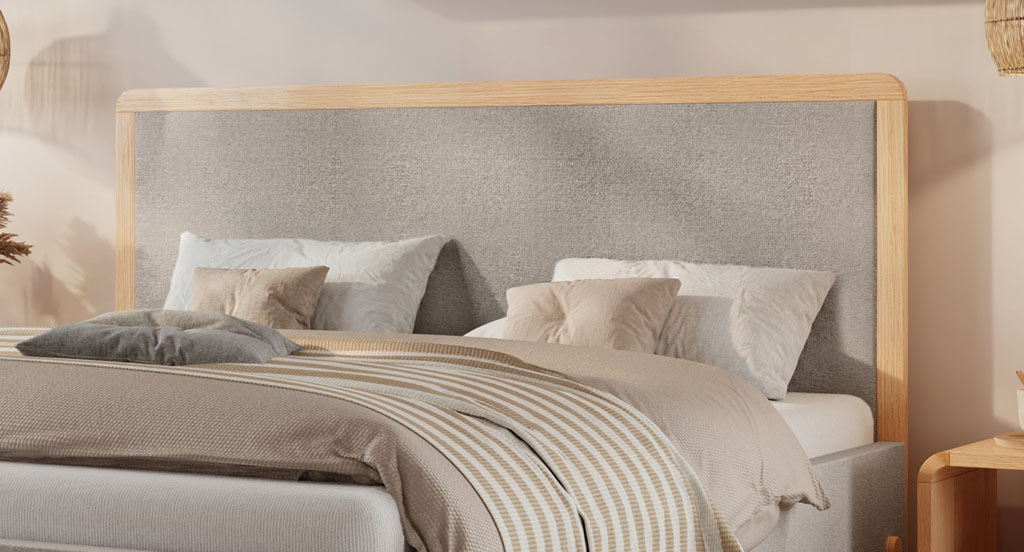 Nahaufnahme des hellgrauen Kopfteils mit massivem Eichenholzrahmen an einem modernen Polsterbett (KI-generiert)