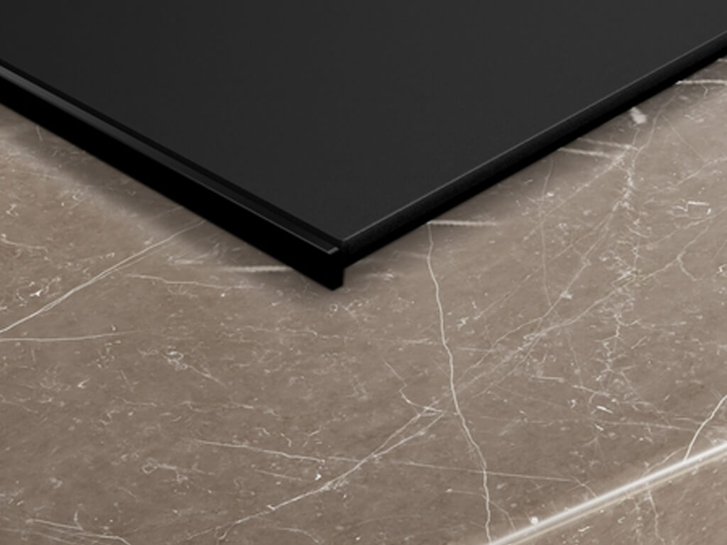 Induktionskochfeld mit aufliegendem Rahmen in einer Mamorarbeitsplatte verbaut.