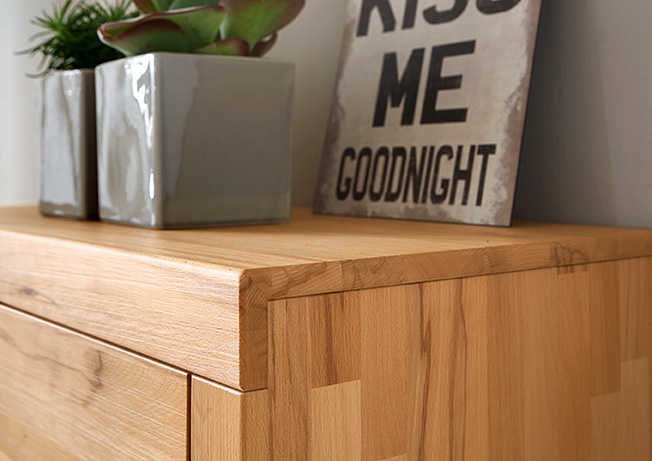 Detailansicht einer Holzkommode mit zwei Pflanzentöpfen und einem 'Kiss Me Goodnight' Schild.