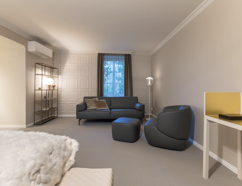 Ein elegantes Wohnzimmer mit grauem Sofa, passenden Sesseln, einem Teppich und stilvoller Beleuchtung.