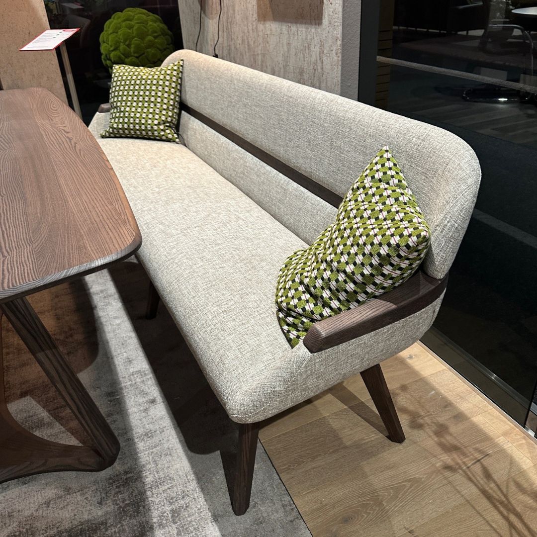 Elegante Polsterbank in hellgrau mit grünen Kissen und Holzelementen an einem Esstisch