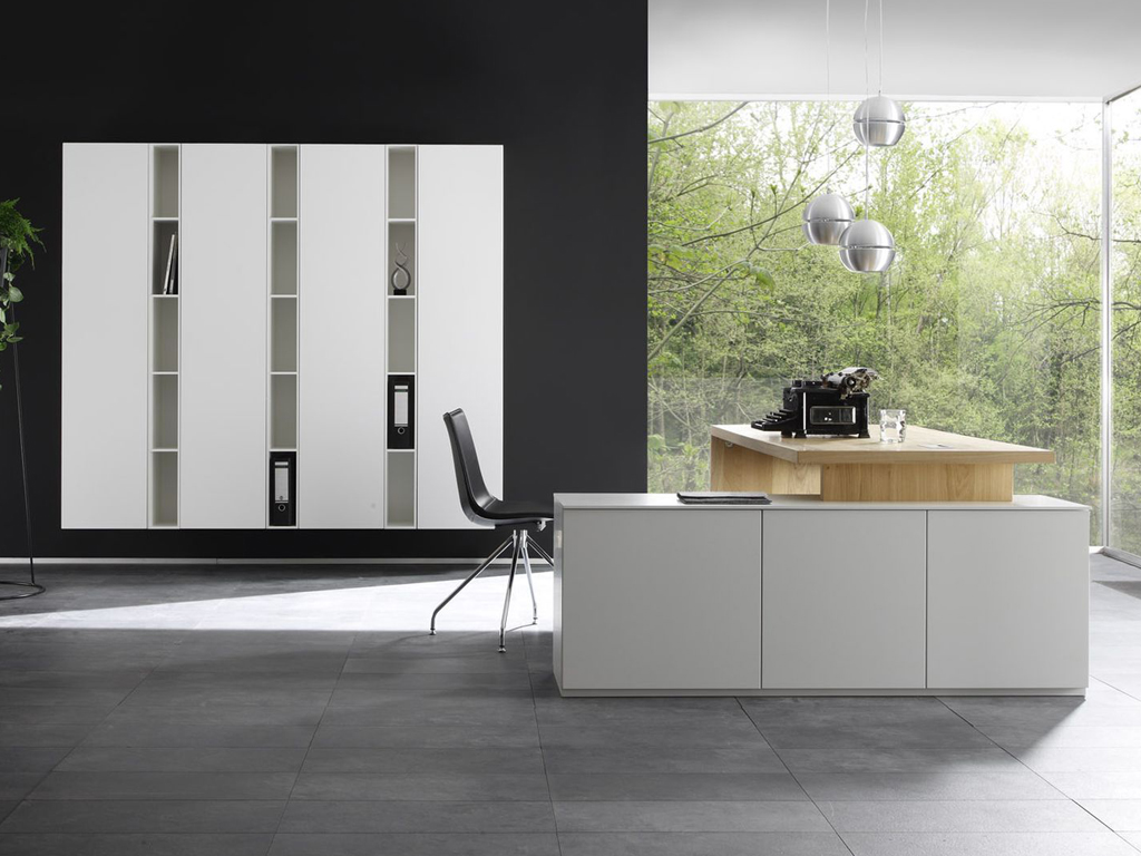 Modernes Büro mit weißem Schrank, schwarzem Stuhl und Holzarbeitsplatte vor einem großen Fenster mit Blick ins Grüne