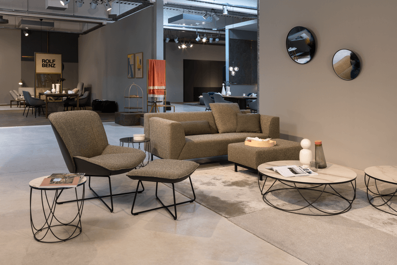 Ein eleganter Raum mit einem modernen Sofa, Sesseln und runden Couchtischen, dekoriert mit zeitgenössischen Accessoires.