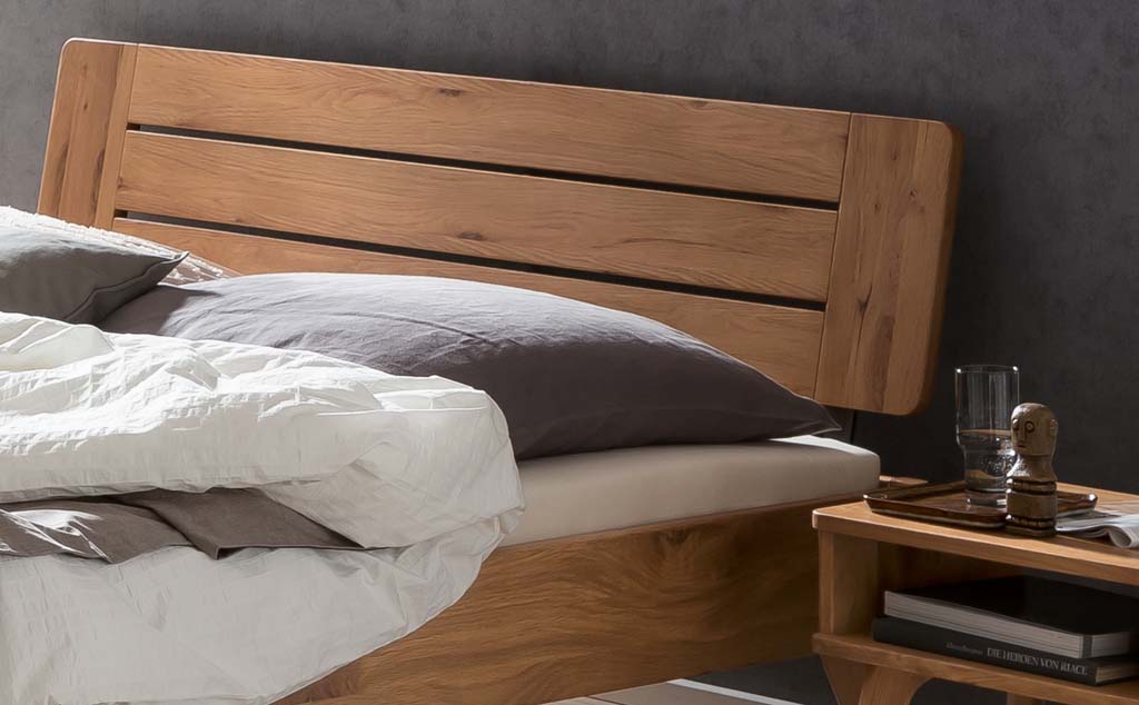 Detailaufnahme eines Holzbettes mit Holzkopfteil und Bettzeug
