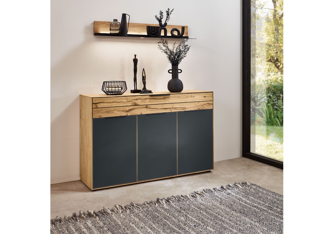 Ein stilvoller Holzschrank mit dunklen Türen, dekoriert mit Vasen und Figuren, steht in einem modernen Wohnzimmer vor einem Fenster mit Blick auf den Garten.