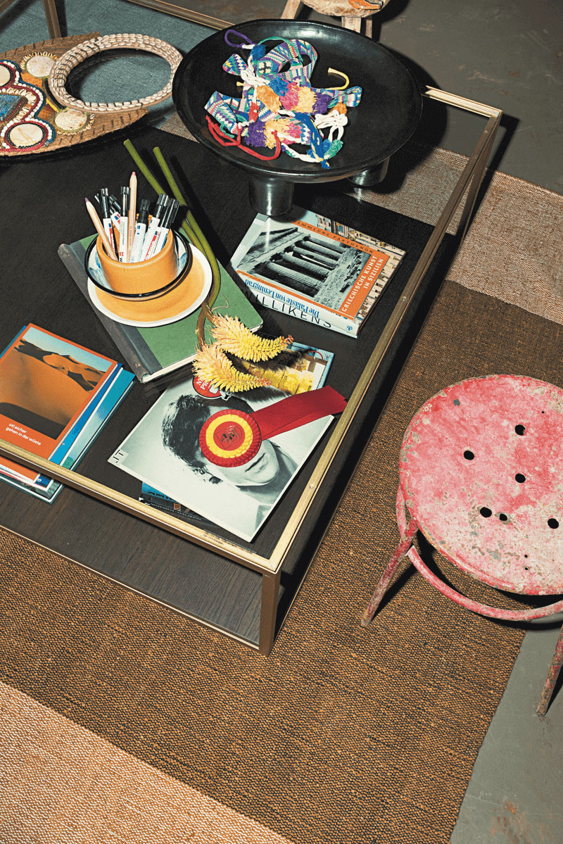Ein Couchtisch mit einer bunten Auswahl an Dekor, Stiften und Büchern, daneben ein vintage Hocker.
