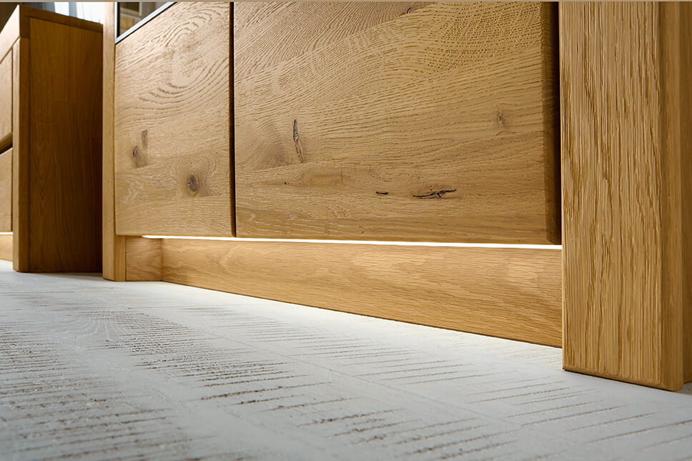 Nahaufnahme eines modernen Holztischs aus hellem Holz mit sichtbarer Maserung auf Betonboden