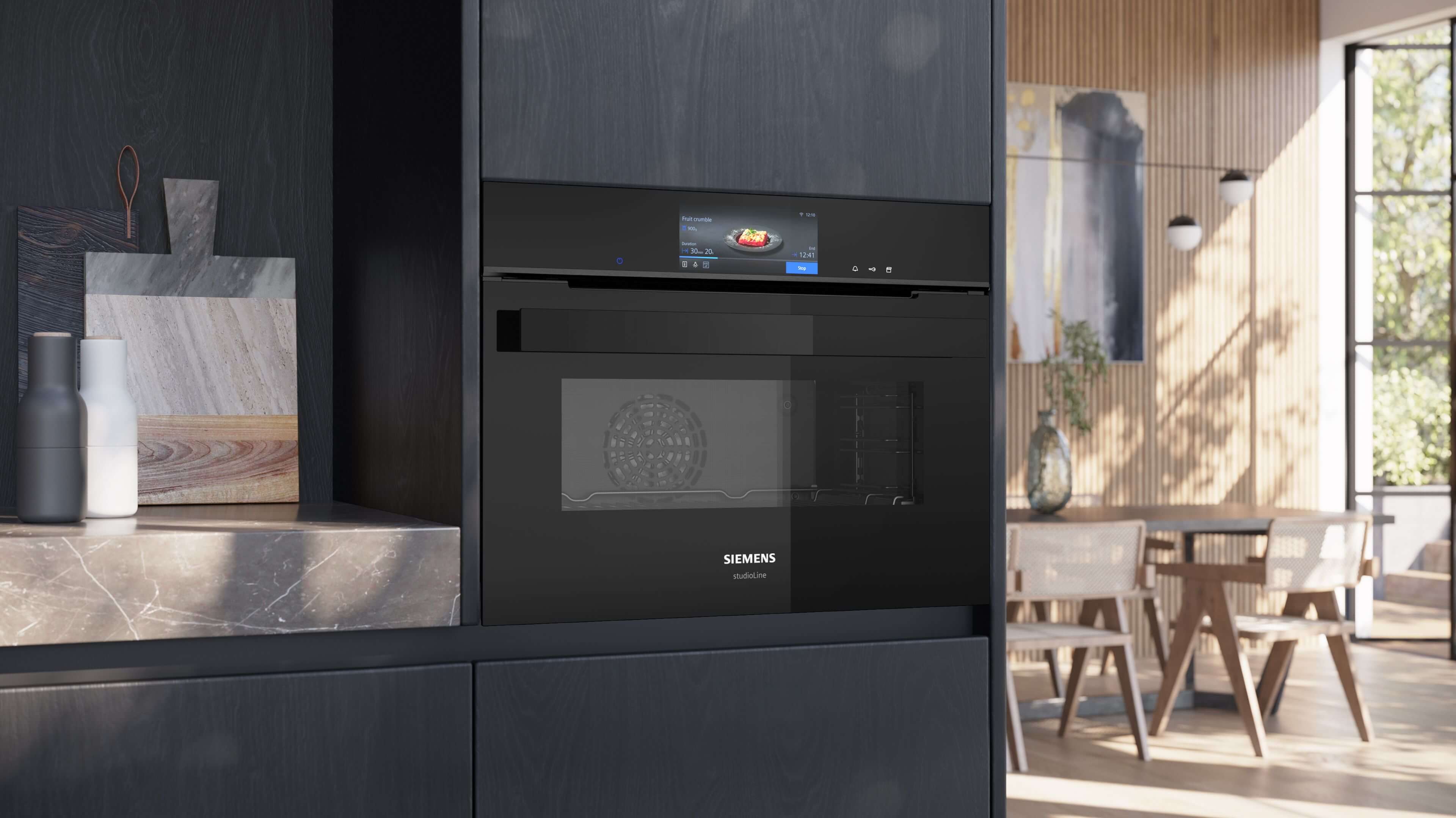 Der schwarze Siemens studioLine Einbaubackofen in einer modernen Küchenzeile mit geschlossener Backofentür und aktivem Display.