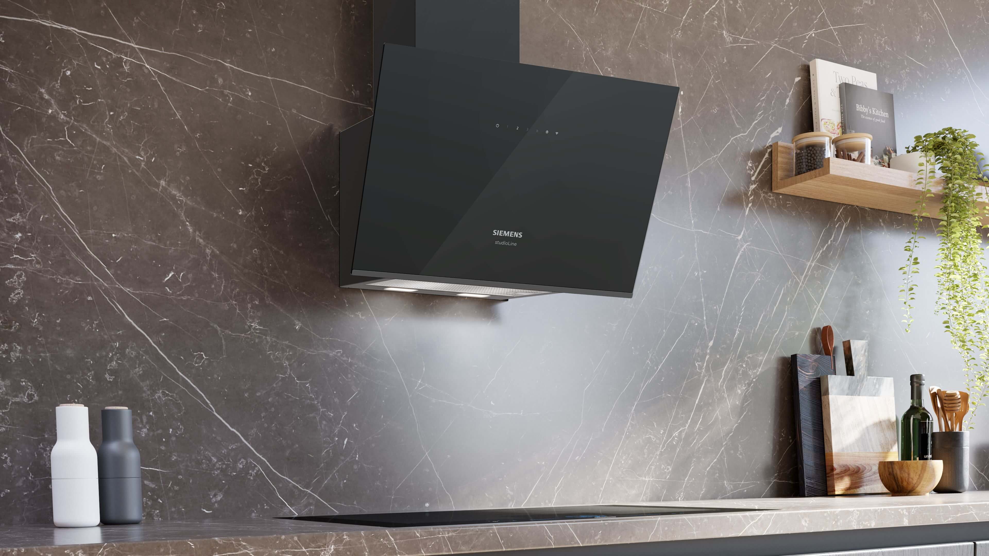 Wandmontierte schwarze Kopffrei-Dunstabzugshaube von Siemens studioLine über einem Kochfeld in einer modernen Küche mit dunkler Marmorwand.