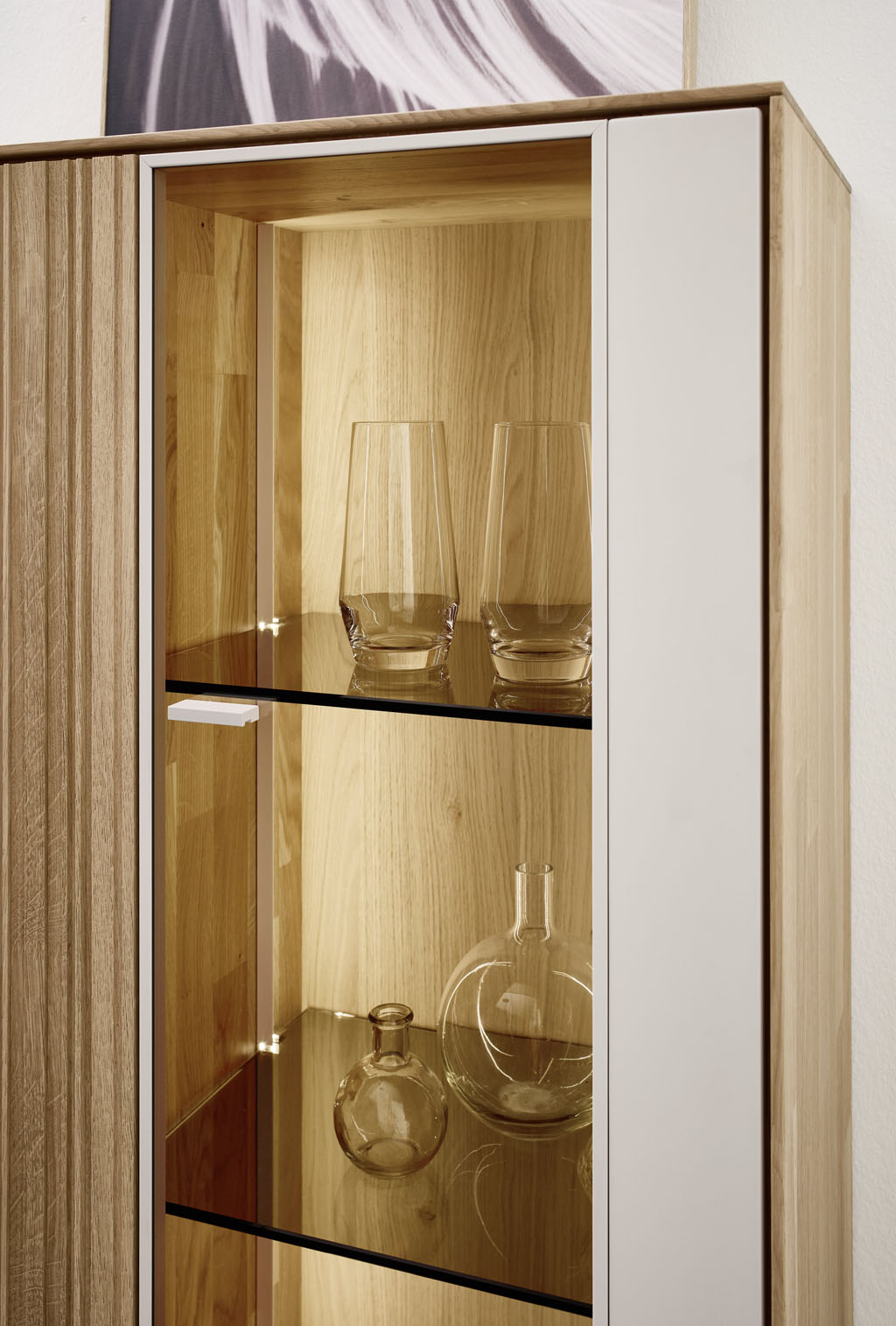 Detailaufnahme eines braun-weißen Vitrinenschrankes mit Beleuchtung stilvoll dekoriert