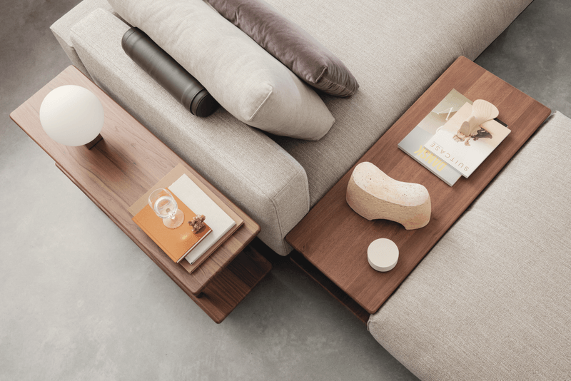 Stilvolles Wohnzimmer mit einem eleganten Sofa, modernen Beistelltischen, Büchern und einem dekorativen Lampenelement.