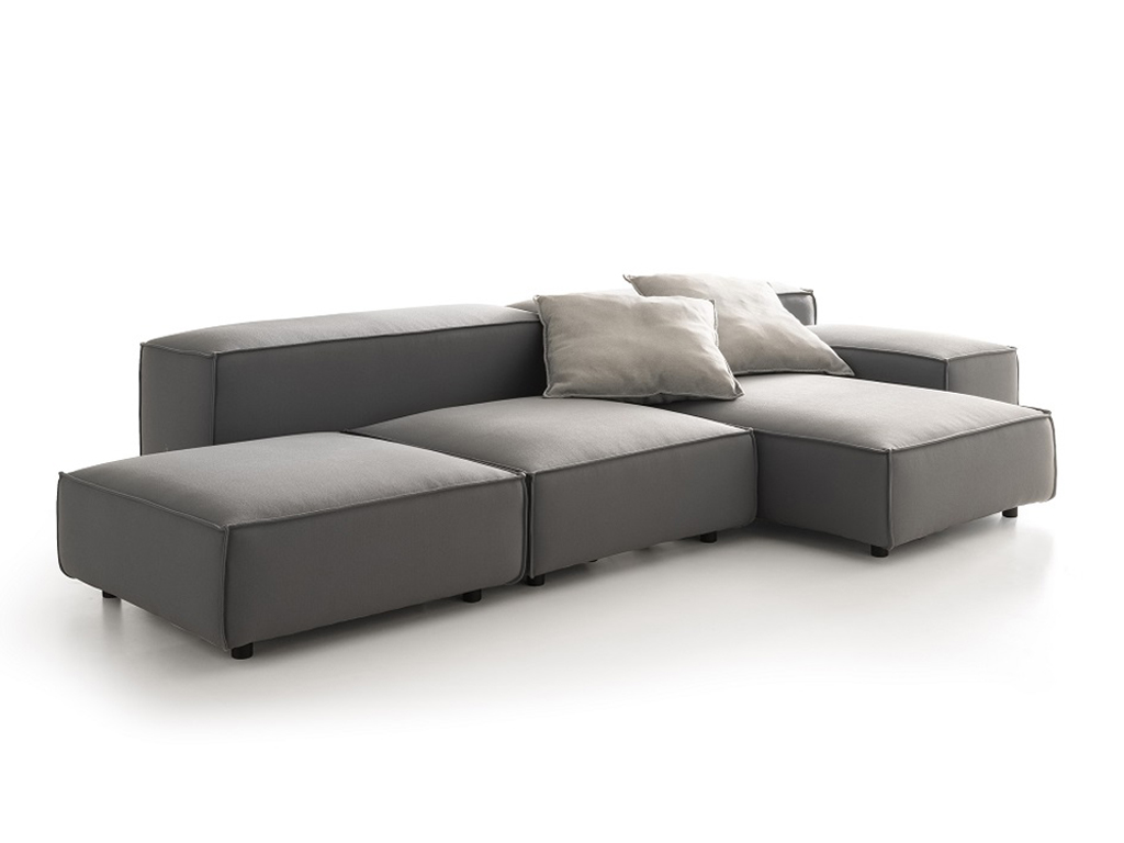Ein modulares Outdoor-Sofa in Dunkelgrau, bestehend aus mehreren Elementen, die zu einer L-förmigen Sitzlandschaft angeordnet sind. Zwei hellbeige Kissen liegen auf den Rückenelementen. Der Hintergrund ist weiß.