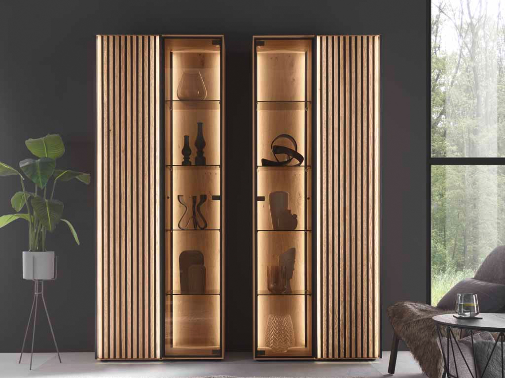 hartmann Selino - Standvitrine | Type 0081/0082 | Birke/Kerneiche massiv, Lack anthrazit | B: 224,0 cm Moderner Vitrinenschrank mit hölzernen Lamellen-Türen und beleuchteten Glasregalen in einem stilvollen Wohnzimmer