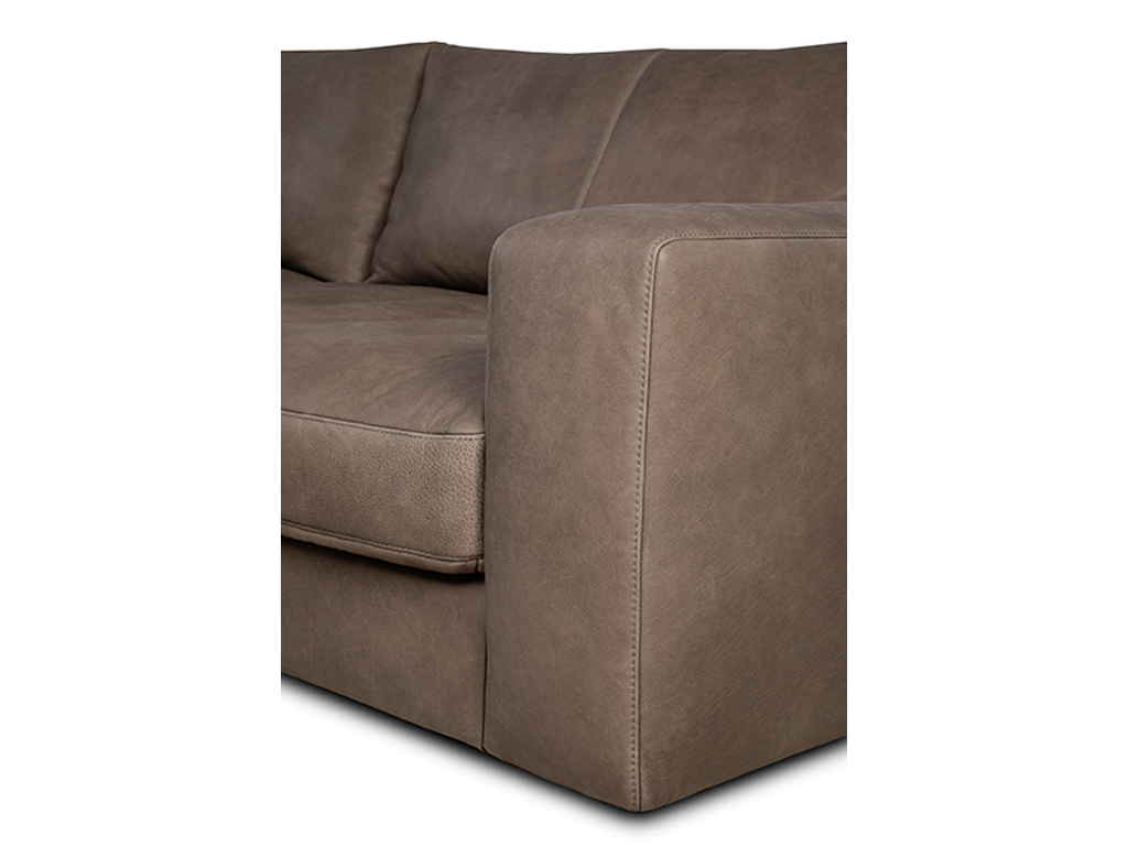 Nahaufnahme der Ecke eines braunen Ledersofas mit sichtbaren Nähten an der Armlehne.