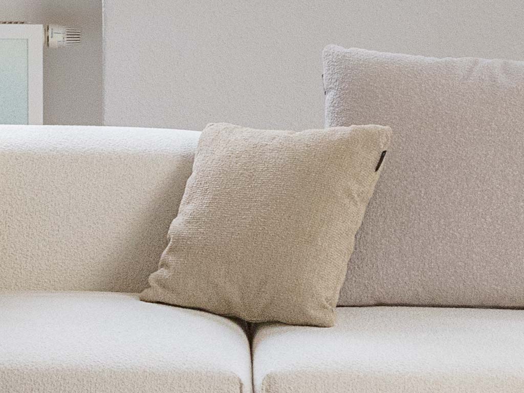 freistil Rolf Benz 122 ECHT - Polsterkissen | 40 x 40 cm Ein beiges Sofa mit einem weichen beigen Kissen in einem hellen, modernen Wohnzimmer