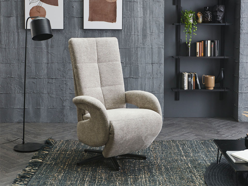 Poco Dayton Style - Relaxsessel Ein moderner grauer Relaxsessel steht in einem stilvollen Wohnzimmer mit grauer Ziegelwand, einem Teppich und einem schwarzen Bücherregal.