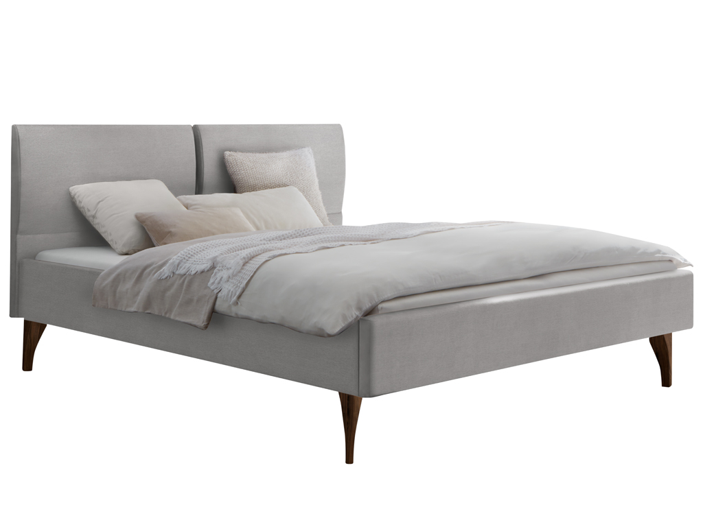 Ein graues, gepolstertes Bett mit einem geteilten Kopfteil und dunklen Holzfüßen, drapiert mit hellem Bettzeug und Kissen.