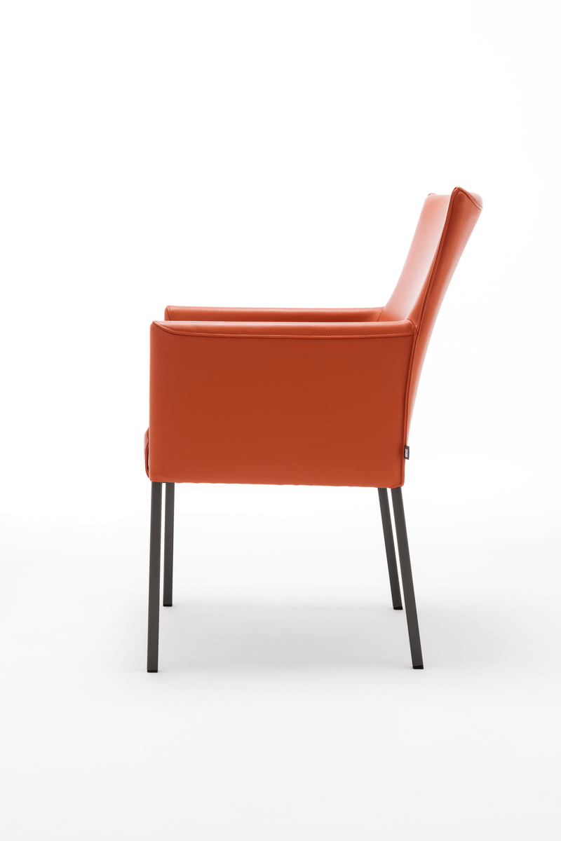 Seitliche Ansicht eines modernen Sessels mit rotem Lederbezug und schwarzen Metallbeinen auf weißem Hintergrund
