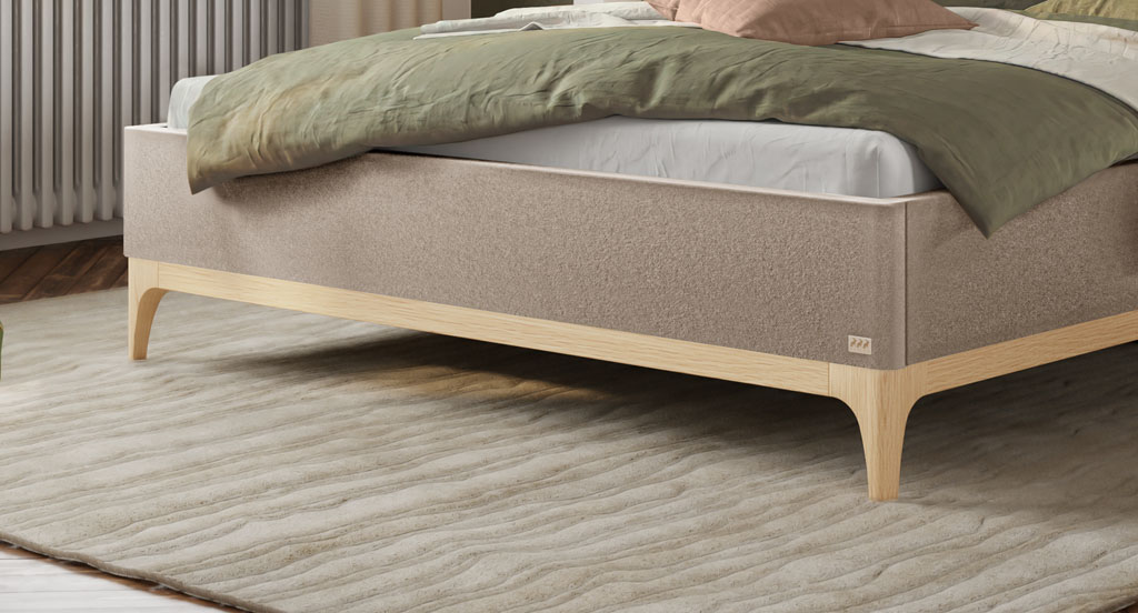 Nahaufnahme der Holzfüße und des Holzrahmens aus heller, geölter Eiche an einem sandfarbenen Polsterbett auf einem Teppich (KI-generiert)