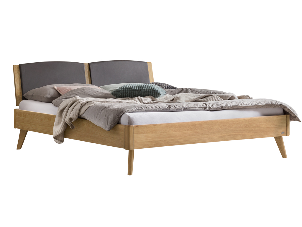 Ein Ansichtsfoto des Hasena Mareto Bettes in der Ausführung Eiche bright (helles Holz) mit einem Kopfteil aus Stoff in der Farbe Kul-smoke (dunkelgrau). Das Bett ist mit Bettwäsche, Kissen und einer Decke dekoriert.
