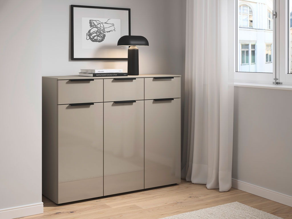 graue Kommode mit schwarzen Griffen, drei Türen und drei Schubladen stilvoll dekoriert in einem modernen Raum