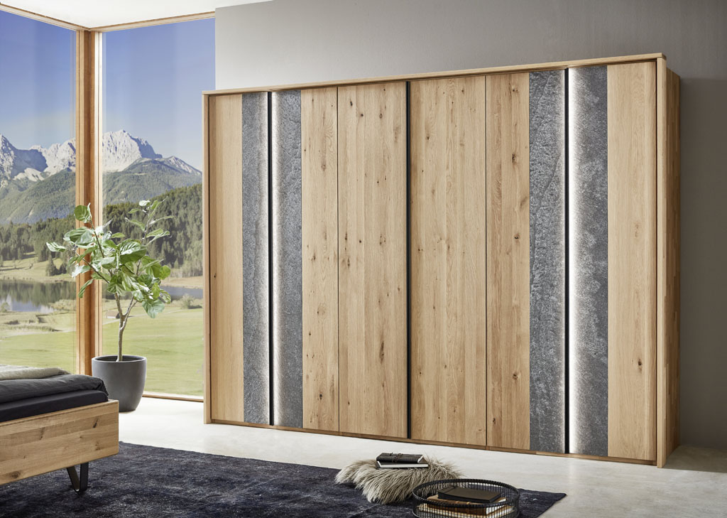 moderner brauner großer Kleiderschrank mit horizontalem grauen Akzent an vier Türen in einem hellen Raum stilvoll dekoriert