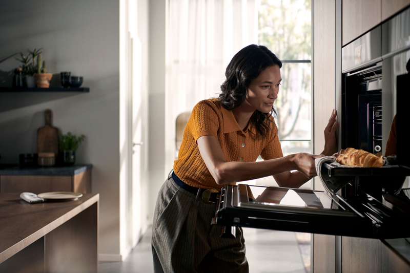 Frau holt Essen aus dem Dampfbackofen