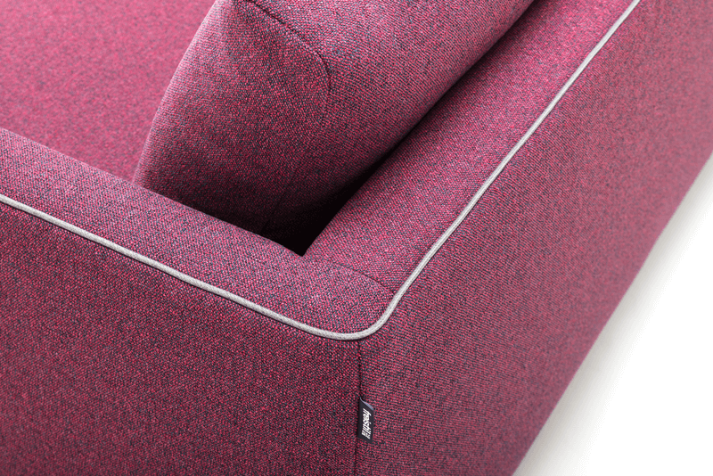 Bildausschnitt eines beerenfarbenen Sofas mit weißer Umrandung. 