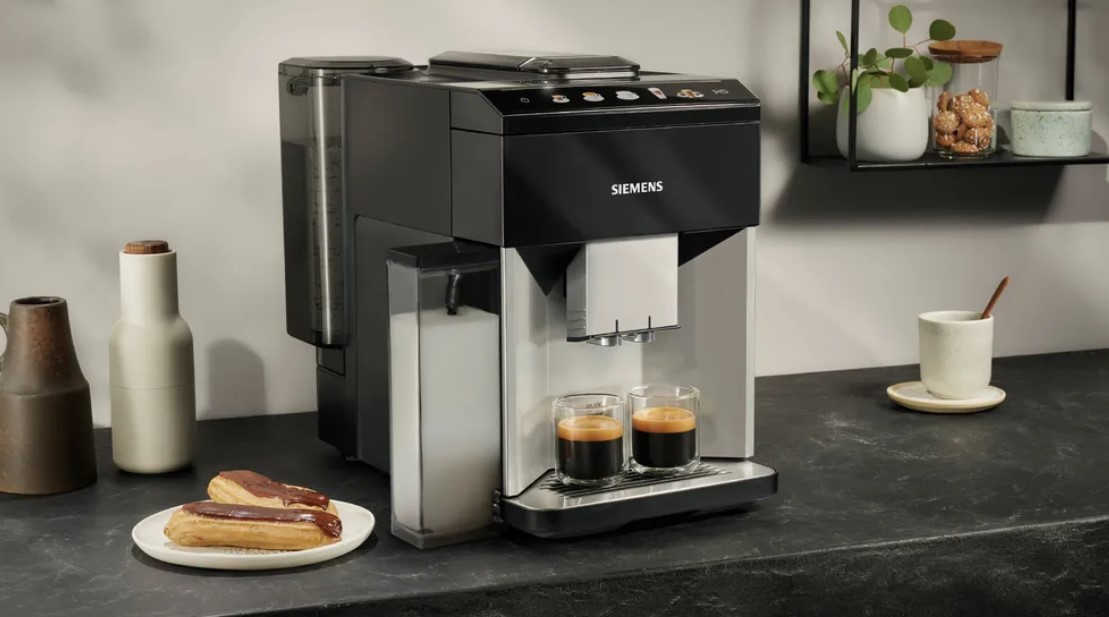 Kaffeevollautomat von Siemens auf einer Küchenarbeitsplatte mit zwei Espresso-Tassen und Gebäck.