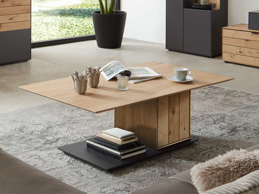 Wöstmann WM 2380 - Couchtisch | Type 9500 | B: 120,0 cm | Wildeiche massiv Moderner Holzcouchtisch mit Büchern und Tasse in einem gemütlichen Wohnzimmer mit Teppich und Pflanzen