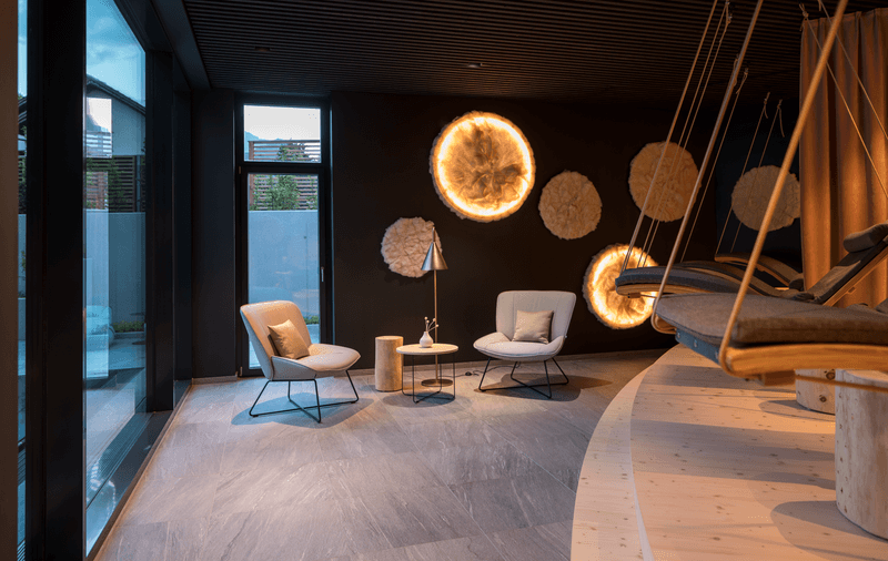 Eleganter Loungebereich mit zwei Sesseln, Beistelltischen und auffälliger Wandkunst in einem modernen Raum