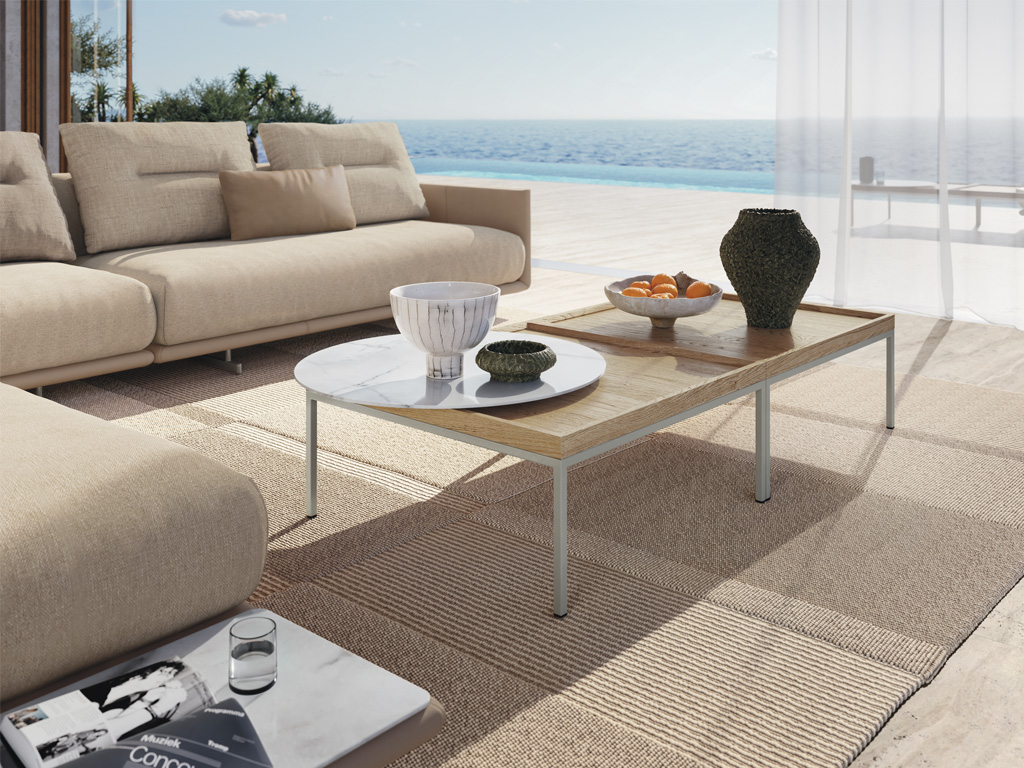 rechteckiger Designercouchtisch mit heller Tischplatte und rundem weißen Tablett stilvoll dekoriert an einer beigen Couch auf beigem Teppich in einem mediterranen Ambiente