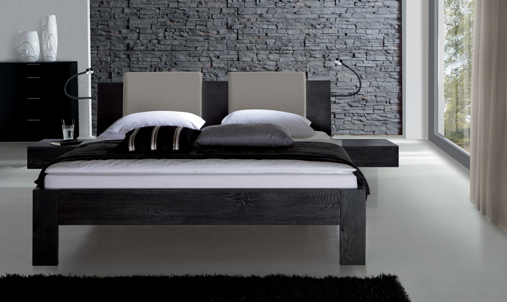 modernes Bett in schwarz mit Holzkopfteil und zwei Polsterkissen am Kopfteil stilvoll dekoriert in einem modernen Zimmer
