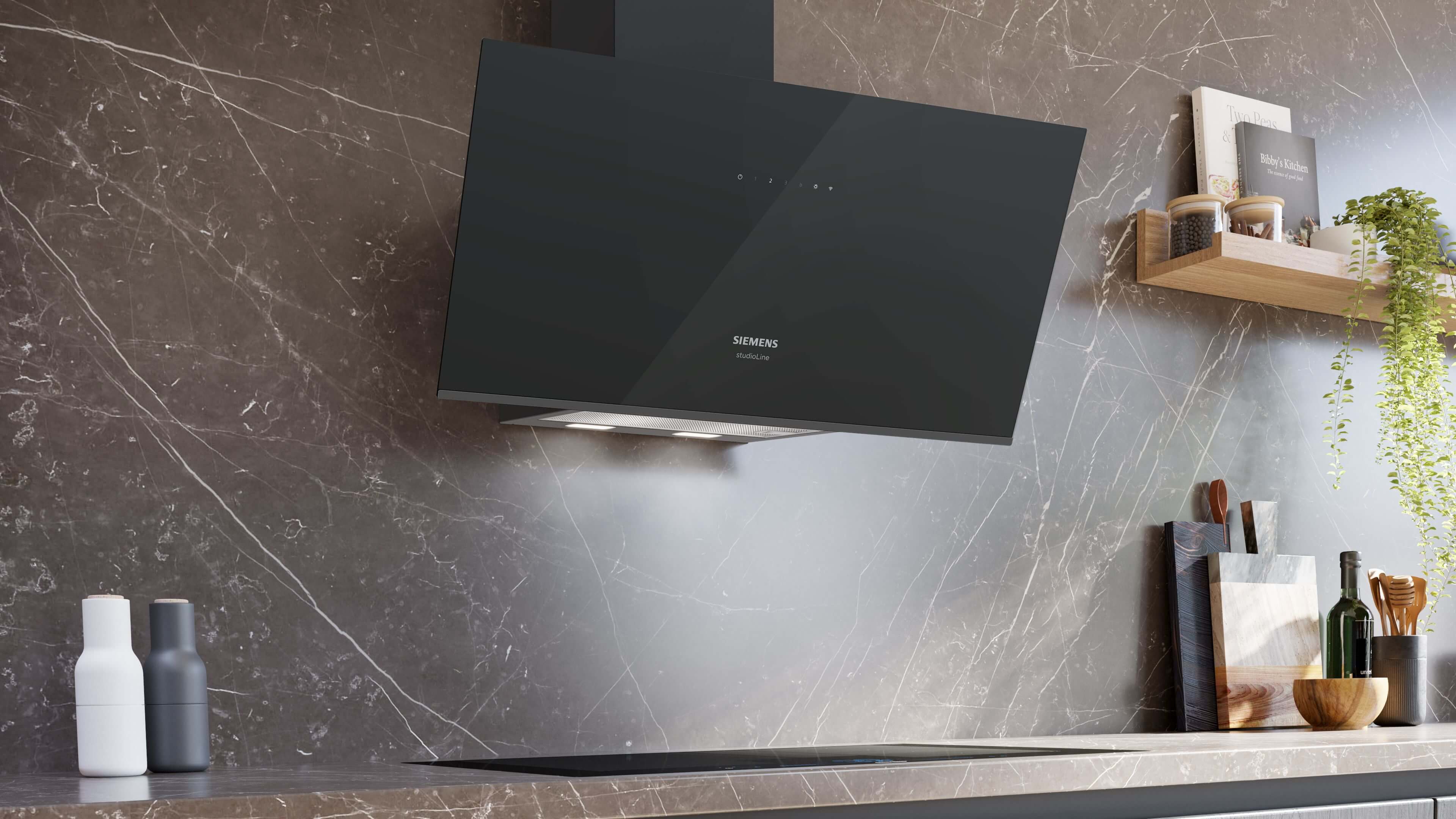 Moderne Küche mit einer an einer dunklen Marmorwand montierten, schrägen schwarzen Glas-Dunstabzugshaube von Siemens studioLine über dem Kochfeld.