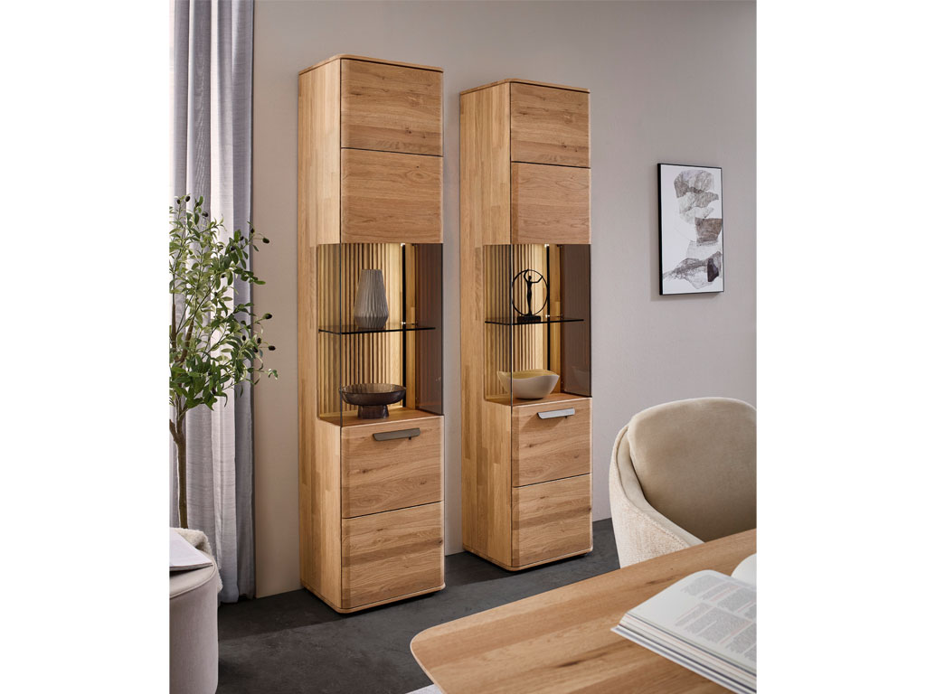 zwei moderne Standvitrinen aus Holz mit großem beleuchteten Vitrinenfach stilvoll dekoriert