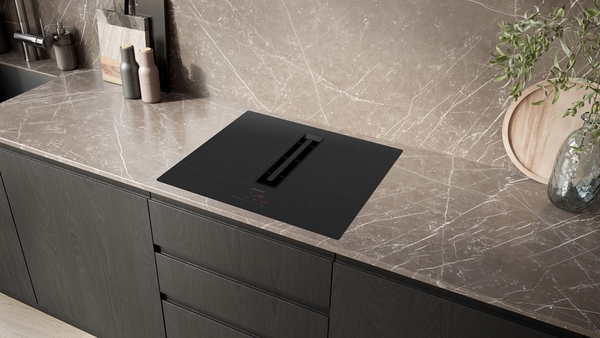 Elegante Küche mit einer Einbau-Induktionskochplatte mit integriertem Dunstabzug auf einer Marmorarbeitsplatte