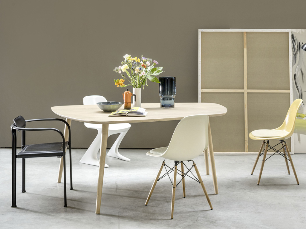 Sudbrock Mellini - Esstisch organisch | B: 170 cm | Eiche milk massiv Essbereich mit drei unterschiedlichen Designerstühlen und einem ovalen Holztisch mit Dekoration und Blumen