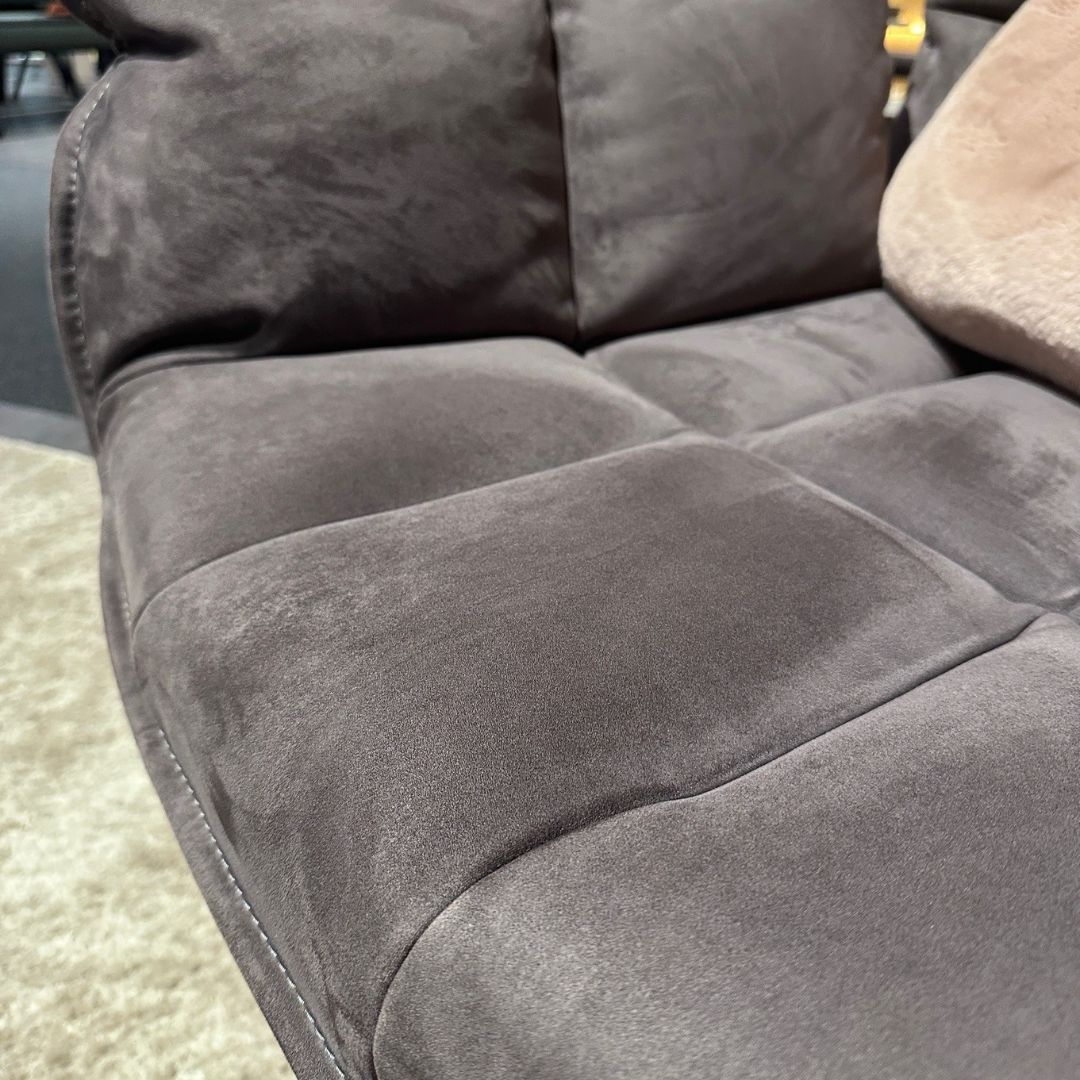 Nahaufnahme eines grauen Sofas mit samtigem Stoffbezug und beiger Decke