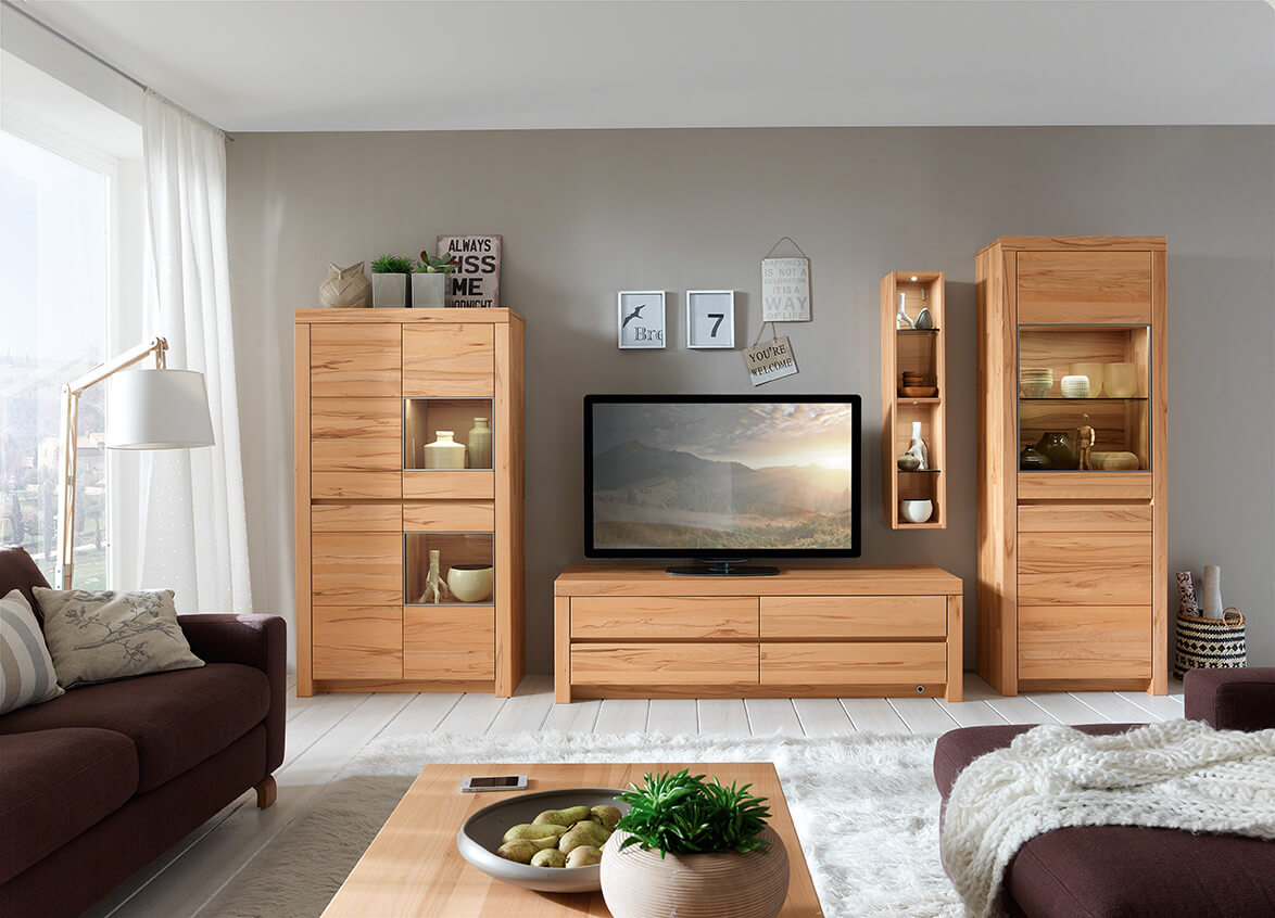 Wöstmann Soleo 3000 - Wohnwand, 4-teilig | Type 3002/3102 | B: 379,1 cm | konfigurierbar Ein modernes Wohnzimmer mit Holzmöbeln, bestehend aus einem TV-Schrank, zwei Vitrinen und einem dekorativen Regal, eingerahmt von einem Sofa und einer Stehlampe.