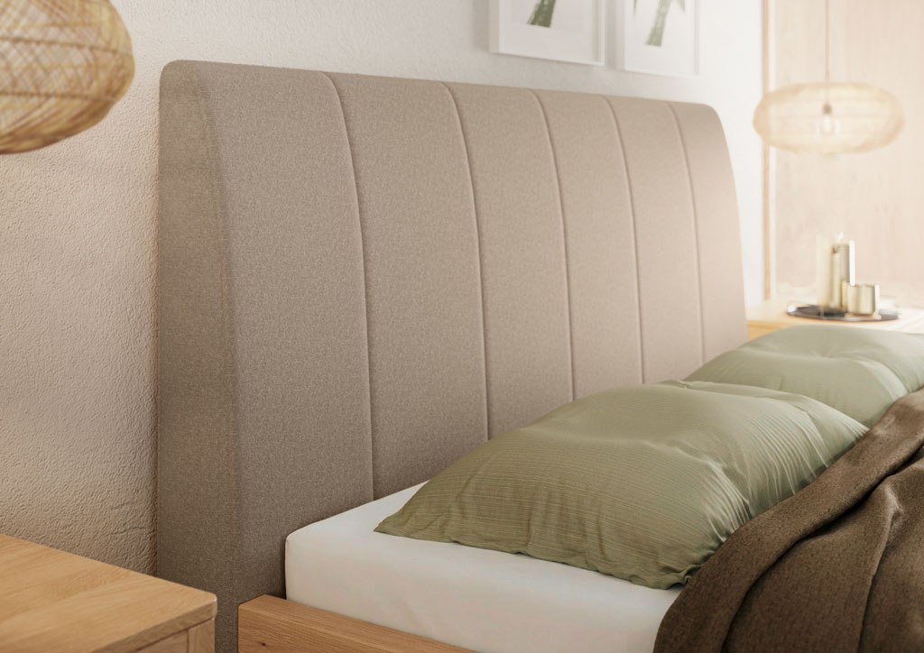 Detailaufnahme eines modernen Polsterbettes mit sandfarbenem Stoff-Kopfteil und vertikaler Steppung in einem hellen Schlafzimmer.