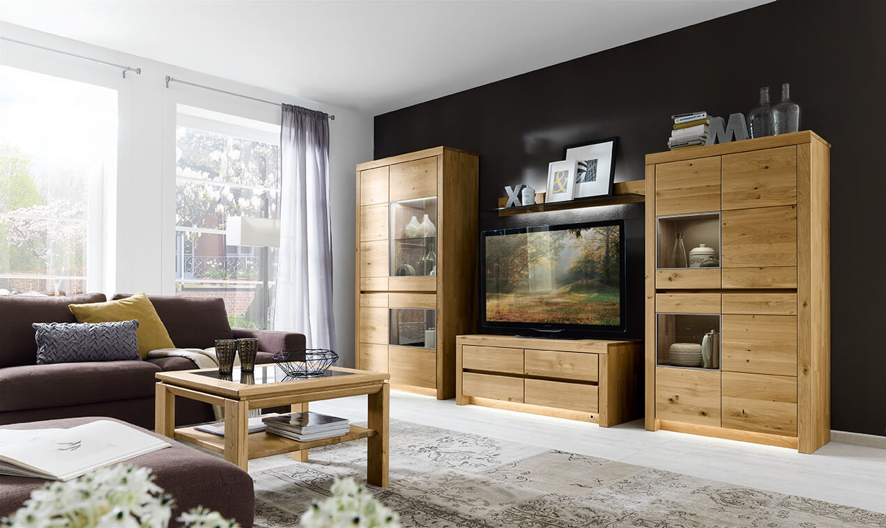 Wöstmann Soleo 3000 - Wohnwand, 4-teilig | Type 3003/3103 | B: 376,9 cm | konfigurierbar Helles Wohnzimmer mit Holzmöbeln, einem modernen Sofa, dekorativen Elementen und einem großen Fenster