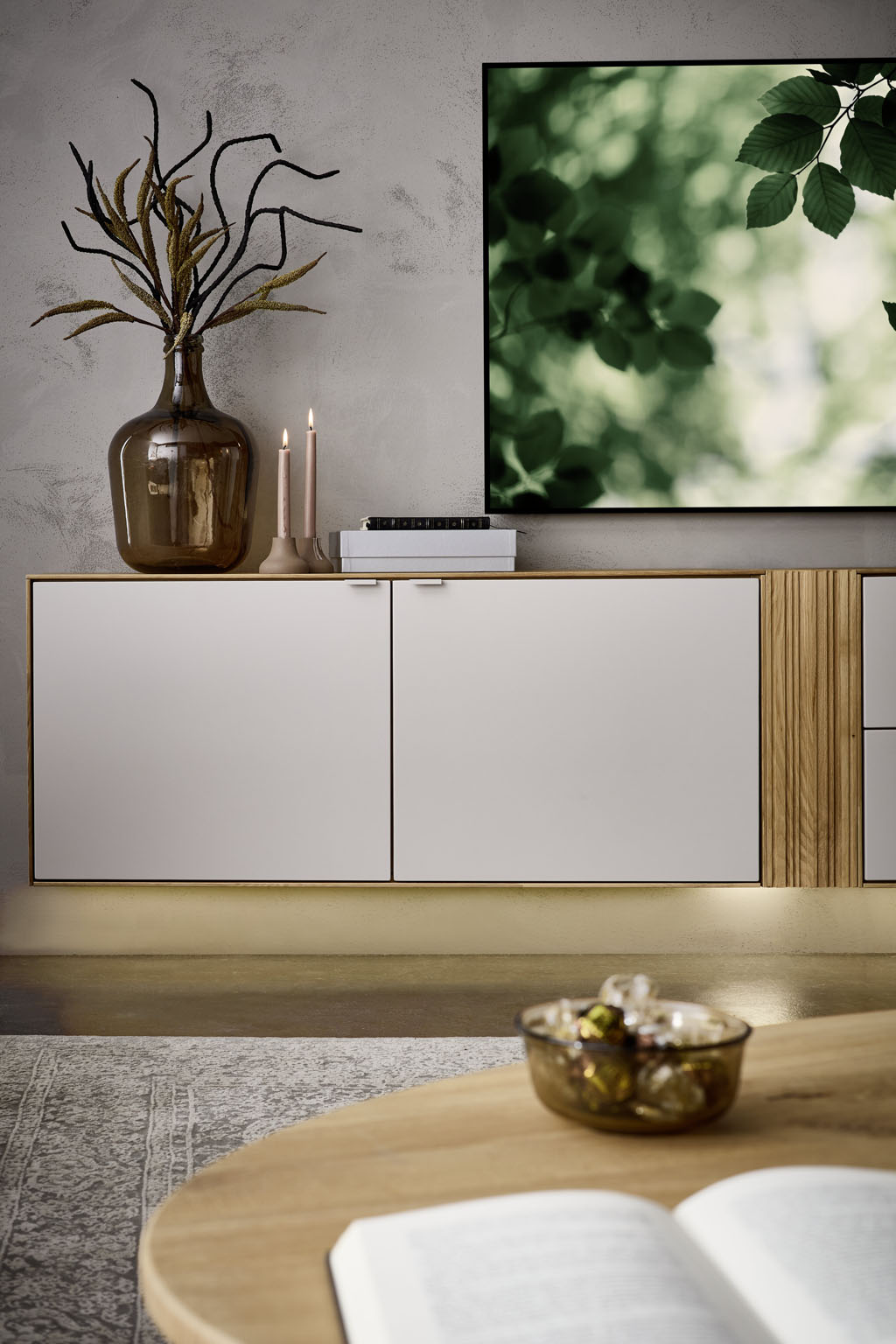 Detailaufnahme eines weiß-braunen Lowboards im Vordergrund ein Couchtisch stilvoll dekoriert