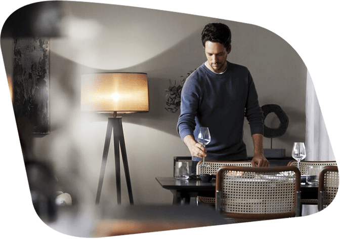 Mann steht in seinem Esszimmer und stellt ein sauberes Glas auf den Tisch.