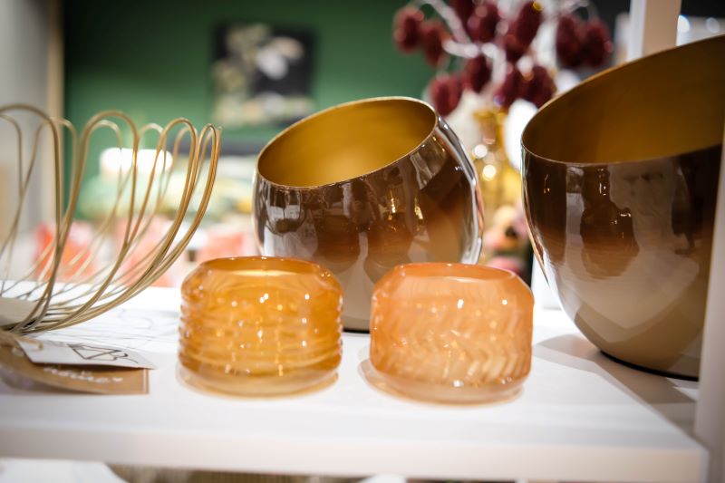 Verschiedene dekorative Glas- und Keramikschalen in warmen Farbtönen auf einem Regal