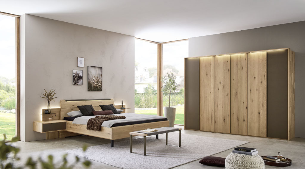 Modernes braunes Schlafzimmer mit einem Schrank mit sechs Türen und einem Bett mit zwei Konsolen stilvoll dekoriert in einem hellen Raum