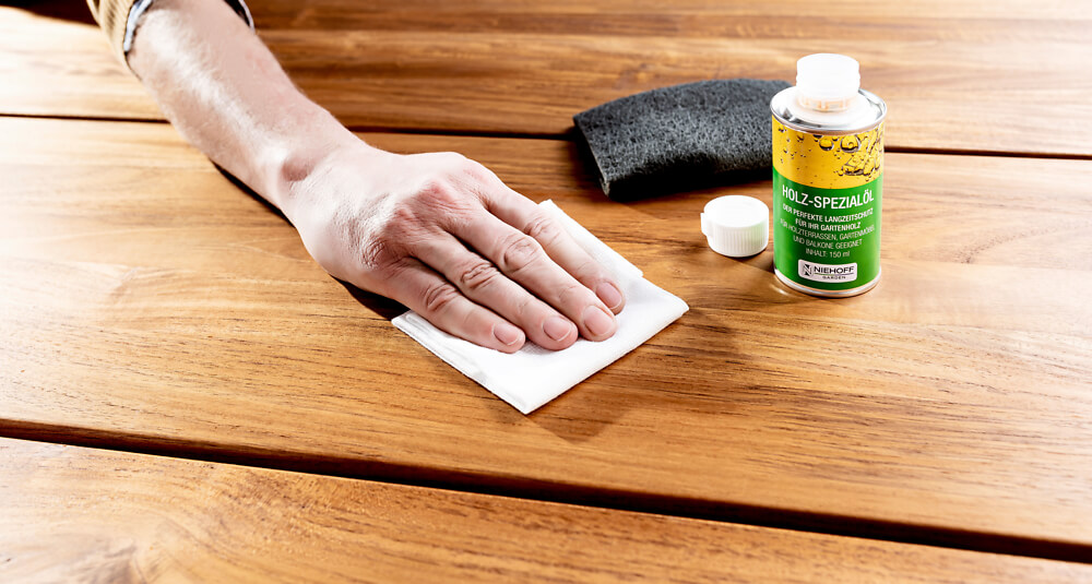 Hand mit Pflegemittel auf Holztisch