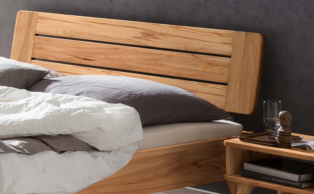 Detailaufnahme eines Holzbettes mit Holzkopfteil und Bettzeug