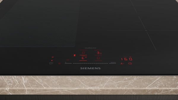Nahaufnahme eines Siemens Induktionskochfelds mit Touchscreen-Bedienelementen auf einer Marmorarbeitsplatte.