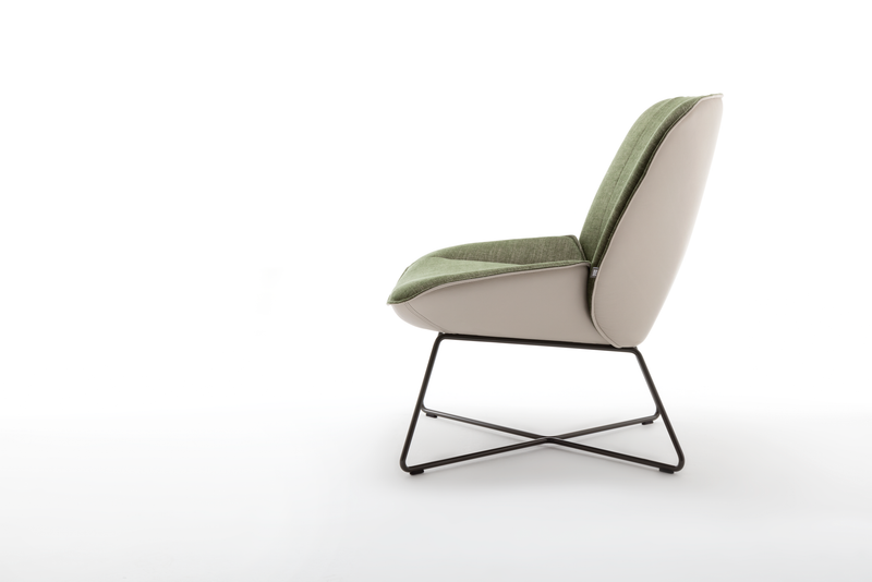 Seitenansicht eines modernen Sessels mit grünem Sitzpolster und weißem Rahmen auf schwarzem Metallgestell